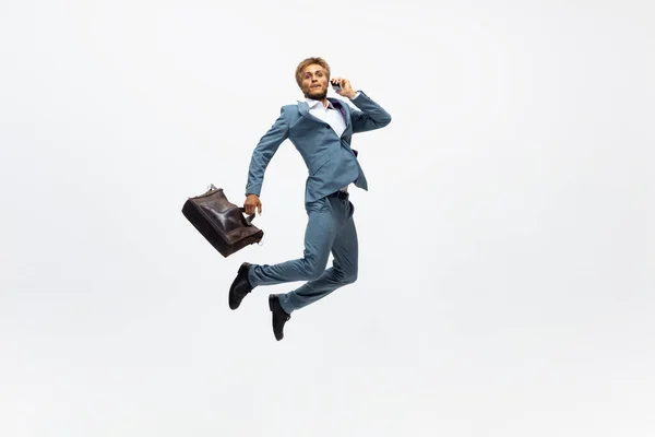 Ένας άντρας με ρούχα γραφείου τρέχει, τρέχει σε λευκό φόντο. Ασυνήθιστο βλέμμα για επιχειρηματία σε κίνηση, δράση. Αθλητισμός, υγιεινός τρόπος ζωής. — Φωτογραφία Αρχείου