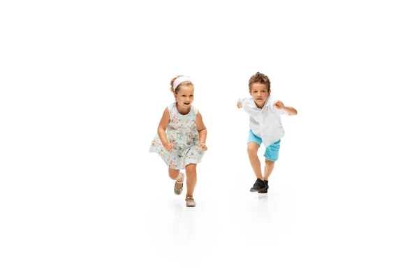 Niños felices, niño y niña caucásicos saltando y corriendo aislados sobre fondo blanco — Foto de Stock