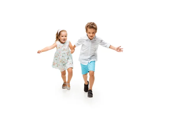 Niños felices, niño y niña caucásicos saltando y corriendo aislados sobre fondo blanco — Foto de Stock