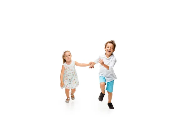 Happy children, little caucasian boy and girl jumping and running isolated on white background — Stock Photo, Image