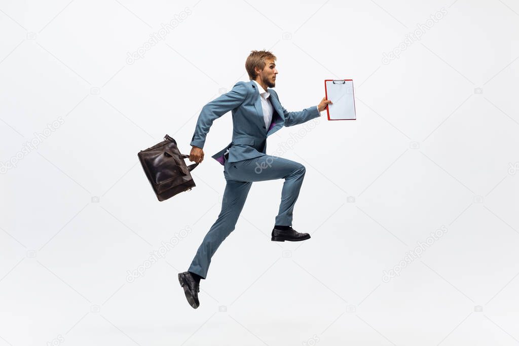 Man in office clothes running, jogging on white background. Unusual look for businessman in motion, action. Sport, healthy lifestyle.