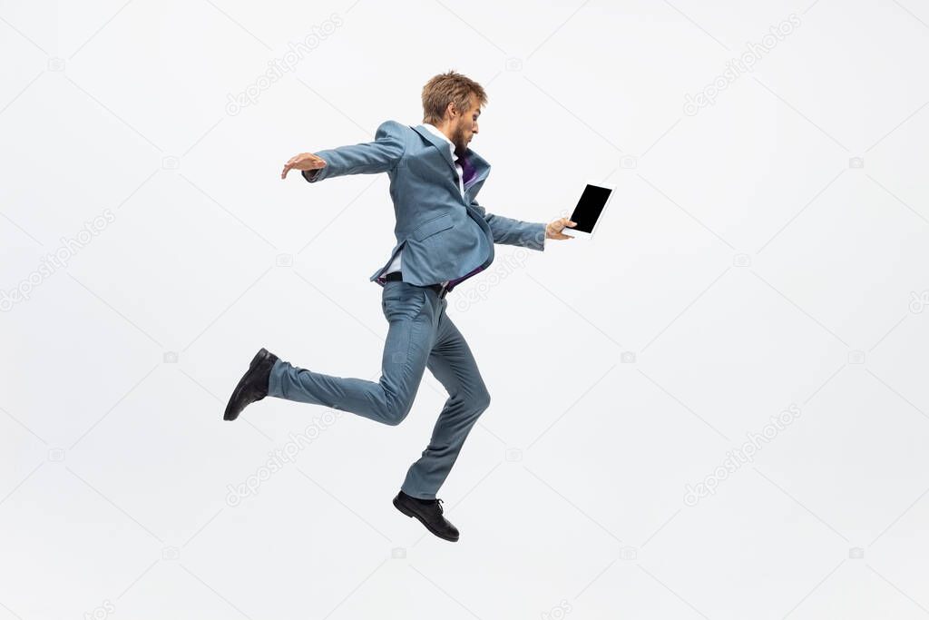 Man in office clothes running, jogging on white background. Unusual look for businessman in motion, action. Sport, healthy lifestyle.