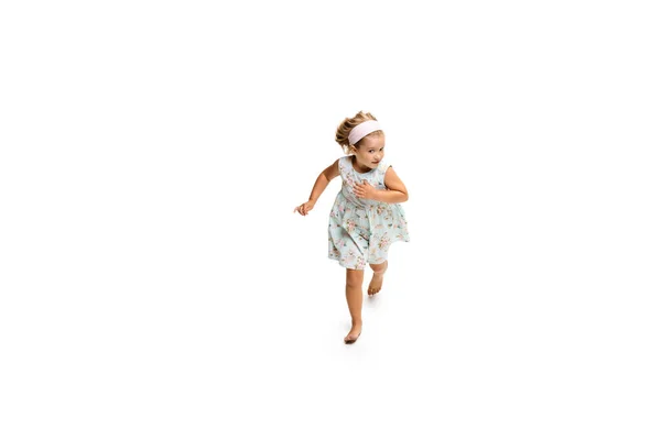 快乐的小高加索女孩在白种人的背景下跳着跑着 — 图库照片