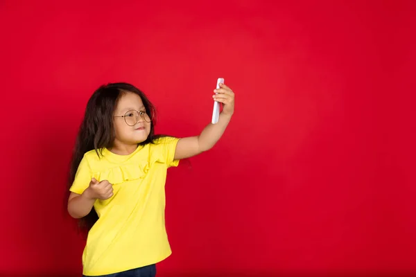 Hermosa niña emocional aislada sobre fondo rojo. Retrato de medio cuerpo de gesto de niño feliz — Foto de Stock