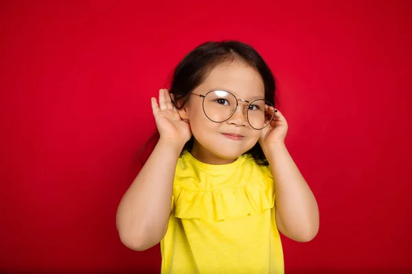 美しい感情的な小さな女の子の赤の背景に隔離された。幸福の子供のジェスチャーのハーフレンズの肖像画 — ストック写真