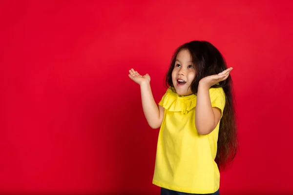 美しい感情的な小さな女の子の赤の背景に隔離された。幸福の子供のジェスチャーのハーフレンズの肖像画 — ストック写真