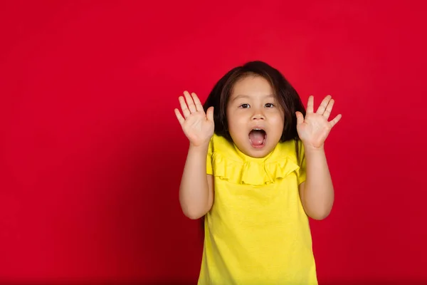 Kırmızı arka planda izole edilmiş güzel, duygusal küçük bir kız. Mutlu çocuk hareketlerinin yarım boy portresi — Stok fotoğraf