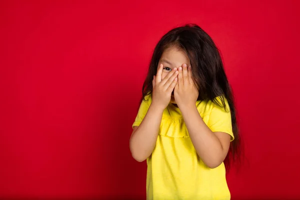 Όμορφο συναισθηματικό κοριτσάκι, απομονωμένο σε κόκκινο φόντο. Το μισού μήκους πορτραίτο του ευτυχισμένου παιδιού που κάνει χειρονομίες — Φωτογραφία Αρχείου