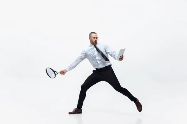 Tijd voor beweging. Man in kantoorkleding speelt tennis geïsoleerd op witte studio achtergrond. — Stockfoto