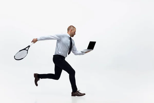 C'est l'heure du mouvement. Homme en vêtements de bureau joue au tennis isolé sur fond de studio blanc. — Photo