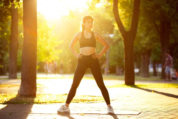 Joven atleta entrenando en la calle de la ciudad bajo el sol del verano. Hermosa mujer practicando, haciendo ejercicio. Concepto de deporte, estilo de vida saludable, movimiento, actividad . — Foto de Stock