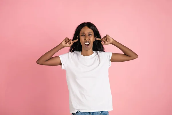 Весела афро-американська молода жінка ізольована на рожевому фоні, емоційна та виразна — стокове фото