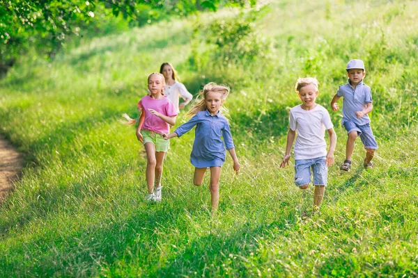 Παιδιά, παιδιά τρέχουν στο λιβάδι τα καλοκαίρια. — Φωτογραφία Αρχείου