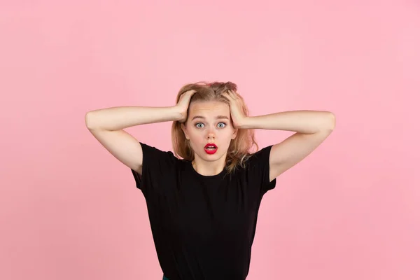 Joven mujer emocional en el fondo del estudio rosa. Emociones humanas, concepto de expresión facial . —  Fotos de Stock