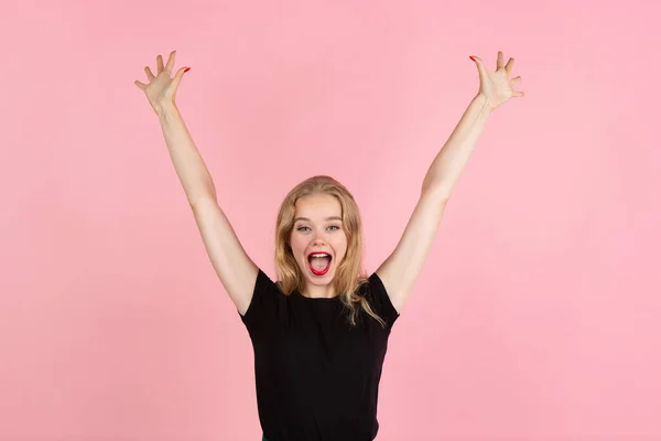 Joven mujer emocional en el fondo del estudio rosa. Emociones humanas, concepto de expresión facial . —  Fotos de Stock