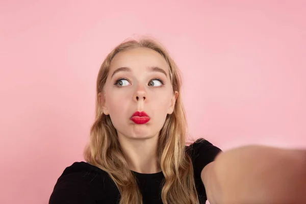 Joven mujer emocional en el fondo del estudio rosa. Emociones humanas, concepto de expresión facial . — Foto de Stock