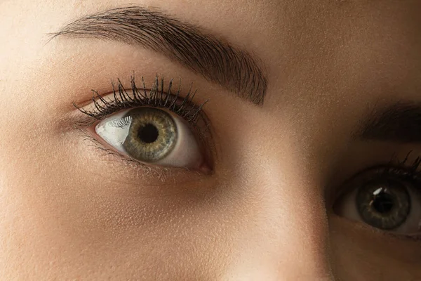 Primo piano del volto di bella giovane donna caucasica, concentrarsi sugli occhi. Emozioni umane, espressione facciale, cosmetologia, corpo e concetto di cura della pelle. — Foto Stock