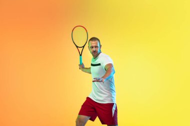 Beyaz tenli profesyonel sporcu stüdyo arka planında neon ışıklı tenis oynuyor.