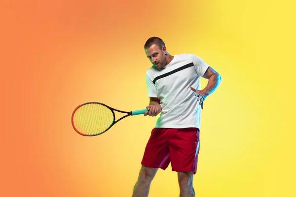 백인 남자 프로 운동 선수, 네온 빛으로 스튜디오 배경에서 테니스를 치는 모습 — 스톡 사진