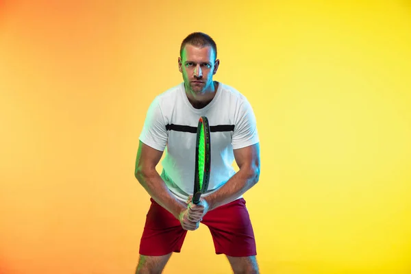 Sportivo professionista maschile caucasico che gioca a tennis su sfondo studio in luce al neon — Foto Stock