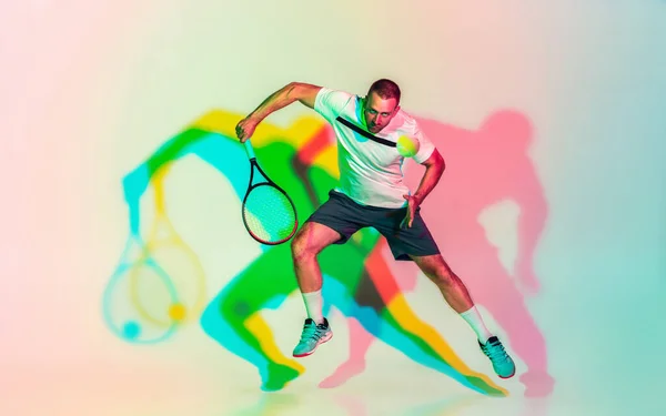 Vit man professionell idrottsman spelar tennis på studio bakgrund i neon ljus — Stockfoto