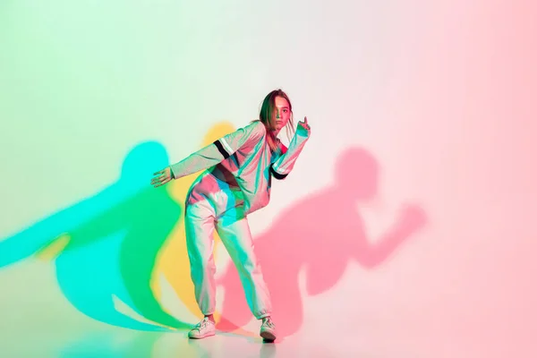 Young beautiful woman dancing hip-hop, street style isolated on studio background in neon light — Stock Photo, Image