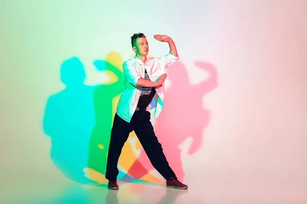 Jovem homem bonito dançando hip-hop, estilo de rua isolado no fundo do estúdio em luz de néon — Fotografia de Stock