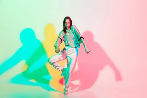 Jovem mulher bonita dançando hip-hop, estilo de rua isolado no fundo do estúdio em luz de néon — Fotografia de Stock