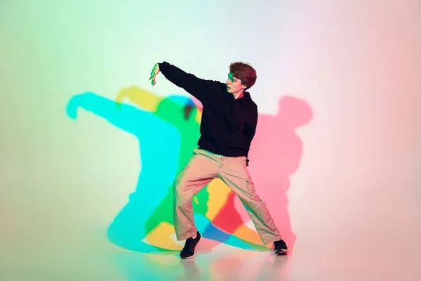 Młody piękny człowiek taniec hip-hop ulica styl odizolowany na studio tło w neon światło — Zdjęcie stockowe
