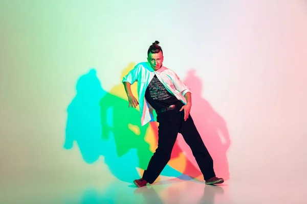 Ung vacker man dansar hip-hop, gata stil isolerad på studio bakgrund i neon ljus — Stockfoto