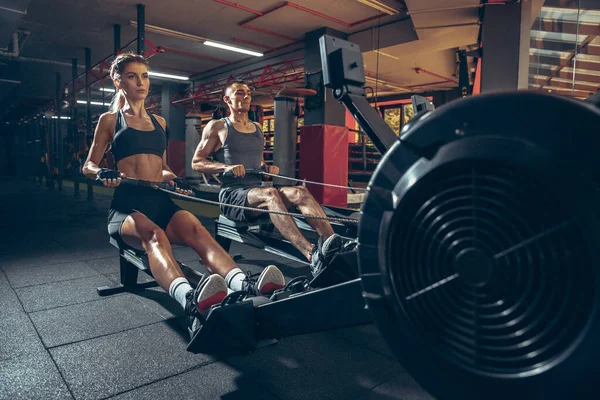 Hermosa joven pareja deportiva de entrenamiento, entrenamiento en el gimnasio juntos — Foto de Stock