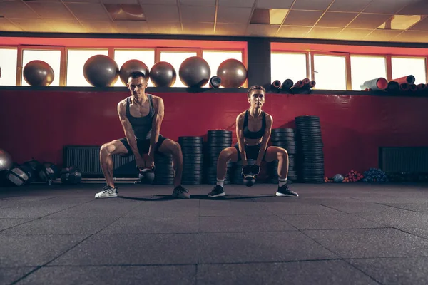 Hermosa joven pareja deportiva de entrenamiento, entrenamiento en el gimnasio juntos — Foto de Stock