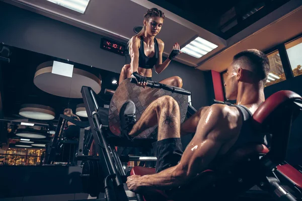 Hermosa joven pareja deportiva de entrenamiento, entrenamiento en el gimnasio juntos — Foto de Stock