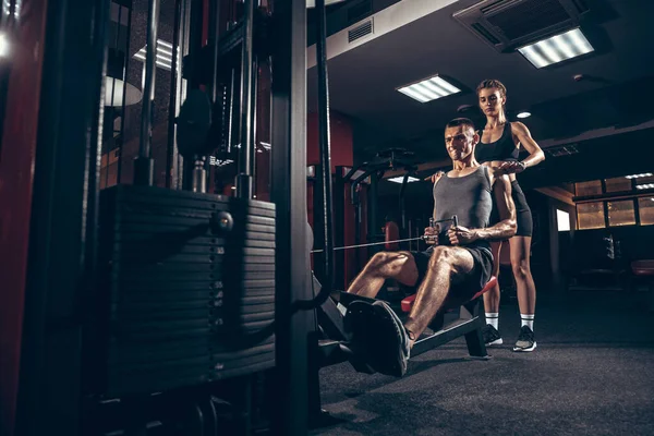 Hermosa joven pareja deportiva de entrenamiento, entrenamiento en el gimnasio juntos — Foto de Stock