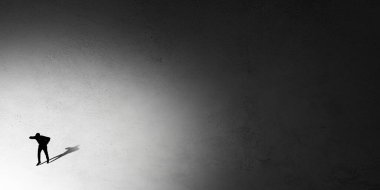 İnsan silueti gecenin içinde ışığa doğru yürüyor, yukarıdan görünüyor.