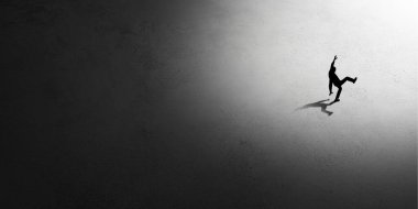 İnsan silueti gecenin içinde ışığa doğru yürüyor, yukarıdan görünüyor.