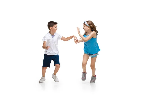 Happy little caucasian girl and boy jumping and running isolated on white background — Stock Photo, Image