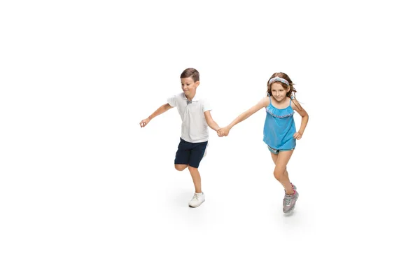 Happy little caucasian girl and boy jumping and running isolated on white background — Stock Photo, Image