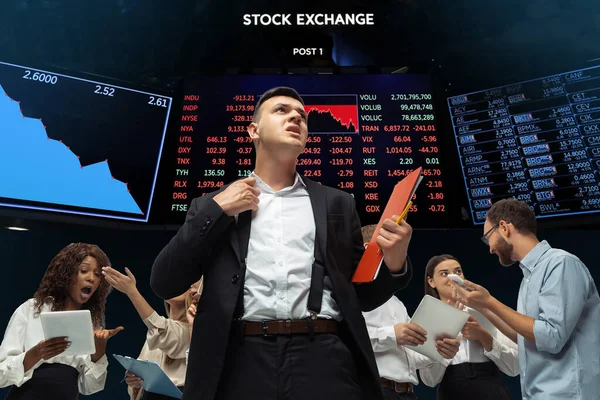 Нервно напряженные инвесторы, анализирующие кризис фондового рынка с графиками на заднем плане, падающей фондовой бирже — стоковое фото