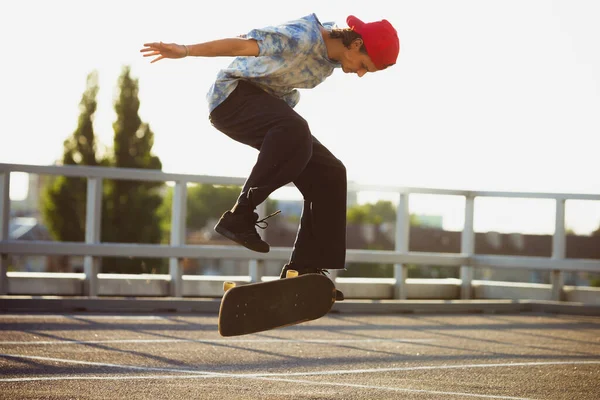 Skateboarder doing a trick at the citys street in summers sunshine — Stock Photo, Image