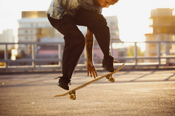 Skateboarder doing a trick at the citys street in summers sunshine — Stock Photo, Image