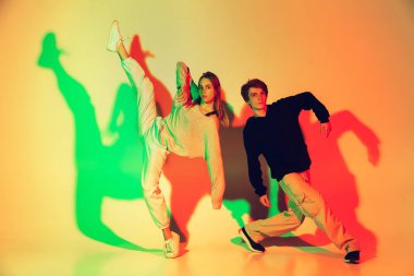 Dans eden genç adam ve kadın hip-hop, sokak tarzı, stüdyo arka planında izole edilmiş, neon ışıklı.