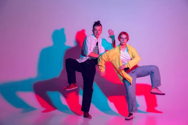 Joven hombre y mujer bailando hip-hop, estilo calle aislado en el fondo del estudio en luz de neón —  Fotos de Stock