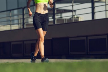 Kadın koşucu, sporcu güneşli yaz günlerinde açık havada antrenman yapıyor..