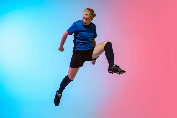 Futebol feminino, jogador de futebol treinando em ação isolado no fundo do estúdio gradiente em luz de néon — Fotografia de Stock