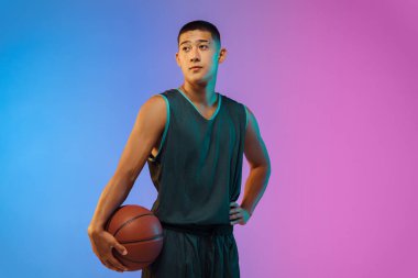 Genç basketbolcu, neon ışığı altında gradyan stüdyo arka planında hareket halinde.