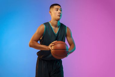 Genç basketbolcu, neon ışığı altında gradyan stüdyo arka planında hareket halinde.