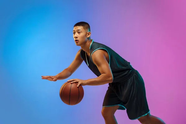 Giovane giocatore di basket in movimento su sfondo gradiente studio in luce al neon — Foto Stock