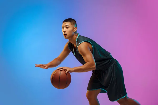 Jovem jogador de basquete em movimento no fundo do estúdio gradiente em luz de néon — Fotografia de Stock