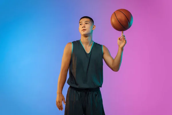 Pemain basket muda bergerak pada latar belakang studio gradien dalam cahaya neon — Stok Foto